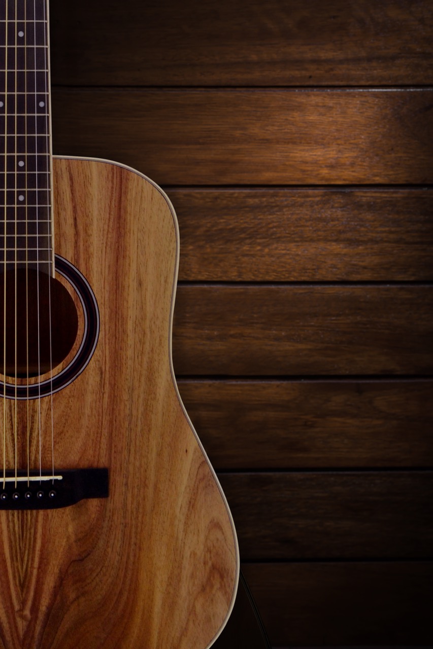 Close-up of a wooden acoustic guitar body against a dark horizontal wooden plank wall.
